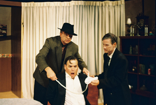 Man in chair being tied up by two other men