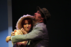 A man in a gray suit and canvas hat hugging a young woman with a white hat