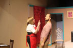 A woman in a red apron arguing with a man