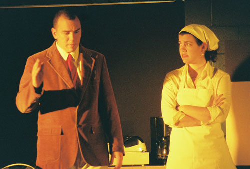 A man in a coat talking to a woman in an apron 