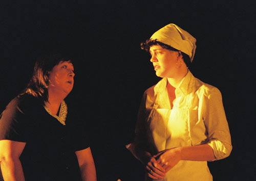 Two women talking, one wearing an apron