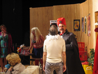 A man wearing zebra-striped pants, a white shirt and a white boa being hypnotized by a man in a black cloak and red turban