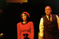 A woman in a red dress standing next to a man in a tie and a vest