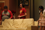A man in a Buccaneers T-shirt, a man in a red Avengers T-shirt and a young woman stand behind a couch