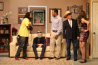 A man in a yellow T-shirt, a man sitting on a couch with a neckbrace and sunglasses, another man, a man in a cowboy hat,
       and a woman wearing a black skirt