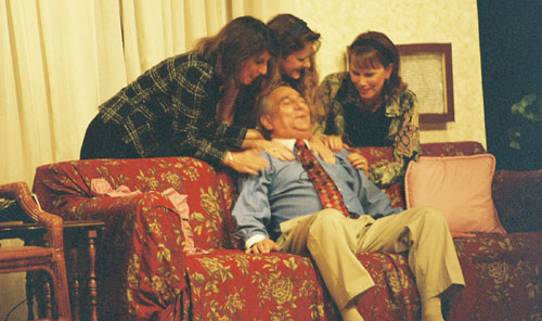 Man on sofa with three woman behind him