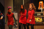 A green alien and two women in red Starfleet uniforms dancing