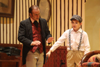 Sherlock Holmes talks to a young boy in suspenders and a cap
