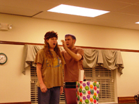 A young boy and a girl singing, the girl wearing a wig