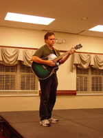 A man standing playing a guitar