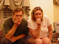 A man and a woman sitting together with their hands over their mouths