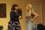 A woman in a dark blouse and floral dress talks to a young woman in a gray T-shirt and jeans